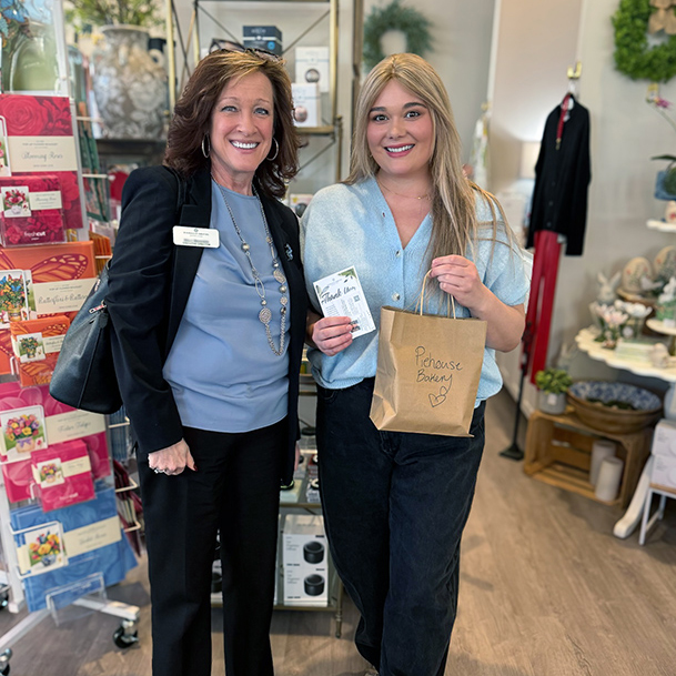 A team member from Pinnacle Groves Senior Living smiles with a local business owner.