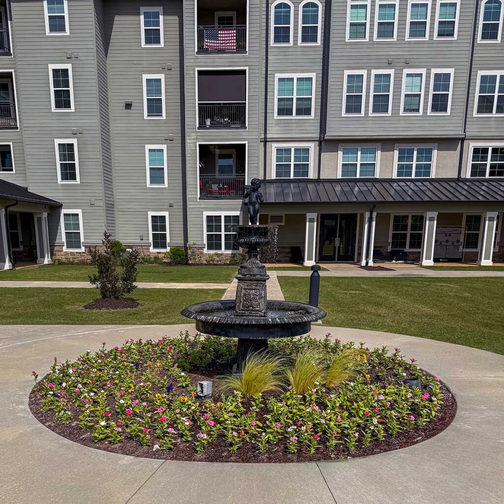 The landscaped grounds at Pinnacle Groves Senior Living, featuring sitting areas and flower beds.