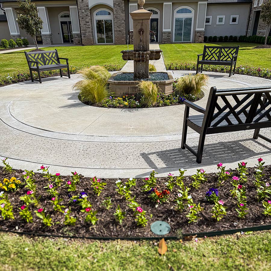 The landscaped grounds at Pinnacle Groves Senior Living, featuring sitting areas and flower beds.