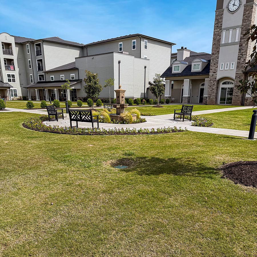 The landscaped grounds at Pinnacle Groves Senior Living, featuring sitting areas and flower beds.